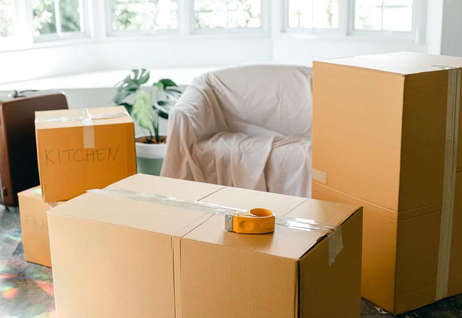 Gepackte Kartons und ein Koffer in einem hellen Wohnraum