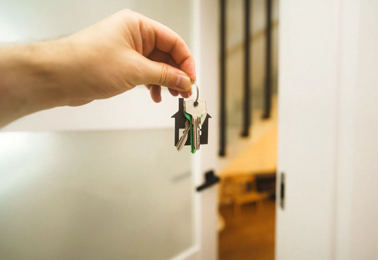Hand mit Hausschlüsseln vor einer geöffneten Wohnungstür